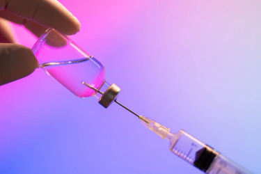 Syringe drawing liquid from a vial.