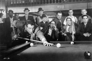 Paul Newman lets a lit cigarette hang from his mouth while lining up a pool shot in a scene from the film The Hustler, 1961. Getty