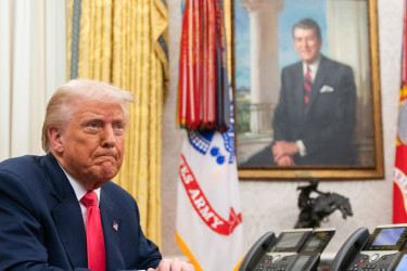 Donald Trump in the Oval Office, with a portrait of Ronald Reagan in the background.