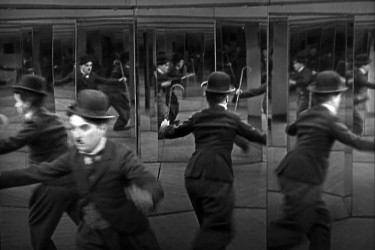 Charlie Chaplin stands fearfully in a hall of mirrors.