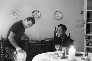 Engin Cezzar and James Baldwin in a dining room.
