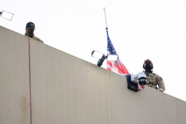 Federal agents loom over a crowd of protesters at the ICE building on September 28, 2025 in Portland, Oregon.