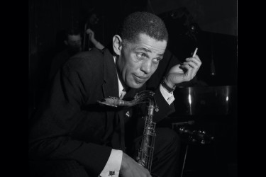 Dexter Gordon holding a cigarette on one hand and holding a saxophone on another