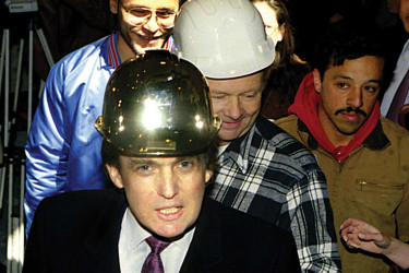 Donald Trump in a gold hardhat poses with construction workers at the Trump Palace.