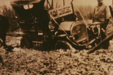 Men digging out a car stuck in the mud.