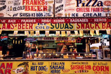 Food stand at a carnival advertising a wide ranging menu.