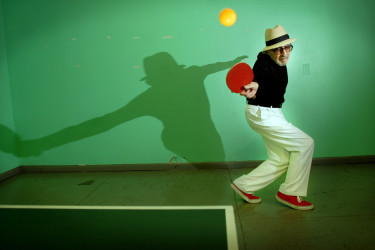 Marty Reisman playing table tennis with the ball in the air.