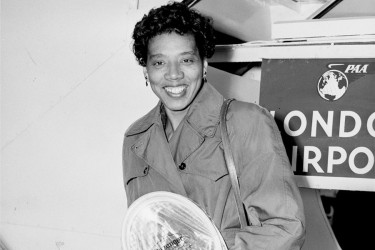 Althea Gibson holding her tennis racket at the London airport.
