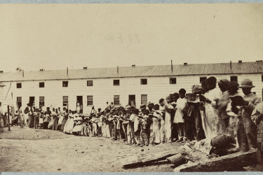 African Americans, including children, gathered in front of a barracks building.