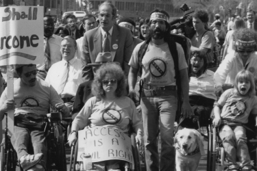 Disability rights demonstrators, some in wheelchairs, one with a seeing-eye dog