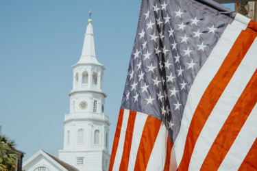 American Flag in front of a church steeple.