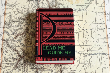 The "Lead Me, Guide Me" hymnal sitting on a map of Colorado.