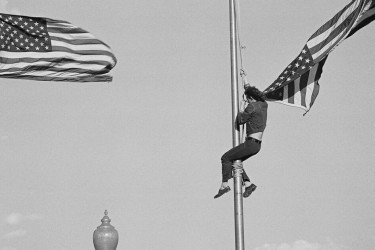A protestor climbs the flagpole to remove the American flag during an Anti-Vietnam War rally in 1971.