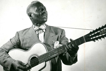 Lead Belly playing a guitar