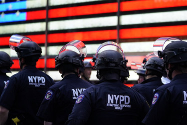 NYPD officers in front of an American flag sculpture.