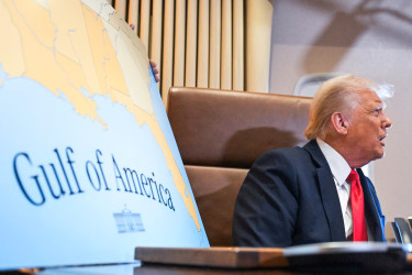 Donald Trump sitting next to a Gulf of America poster.