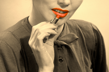 A woman applying red lipstick.