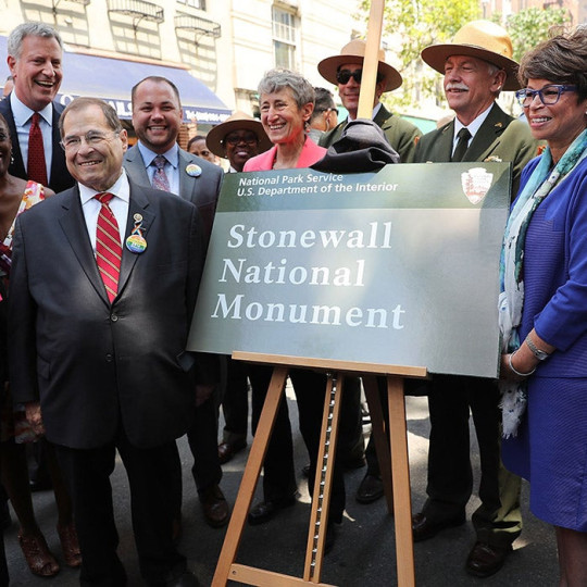 People pose next to a National Park Service sign for the Stonewall National Monument.