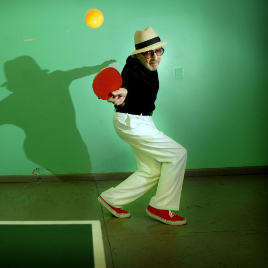 Marty Reisman playing table tennis with the ball in the air.
