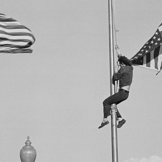 A protestor climbs the flagpole to remove the American flag during an Anti-Vietnam War rally in 1971.