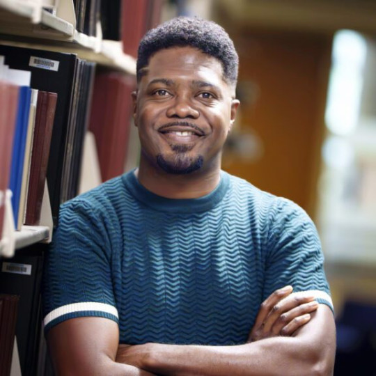 Jarvis McInnis in a library, smiling at the camera.