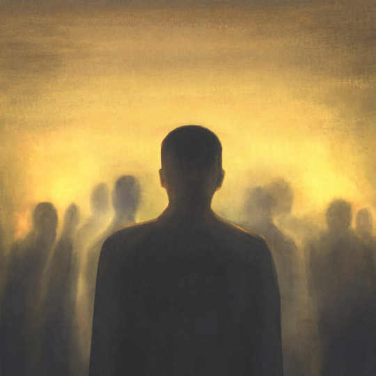 Silhouette of a person standing apart, looking at with blurred, shadowy figures huddled around a bright light.