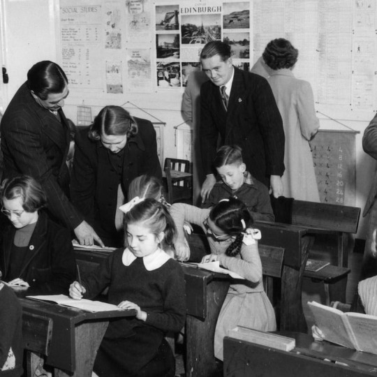 Adults supervise children reading at school