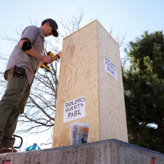 A worker boards up the pedestal where a bust of the late United Farm Workers union co-founder César Chávez previously stood in Denver’s Cesar Chavez Park as signs reading “Dolores Huerta Park” are pasted onto the wooden boards (OSV News photo/Kevin Mohatt, Reuters).