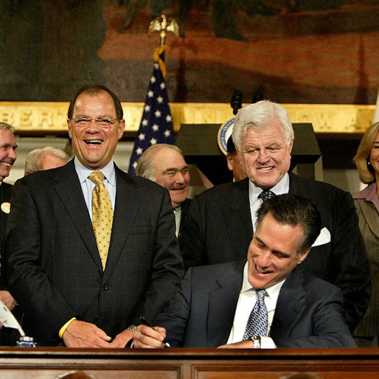 On April 12, 2006, then-Gov. Mitt Romney signed into law what would be dubbed “Romneycare,” as various state political leaders, including Sen. Edward M. Kennedy, looked on. (Photo by David L Ryan/Boston Globe via Getty Images)