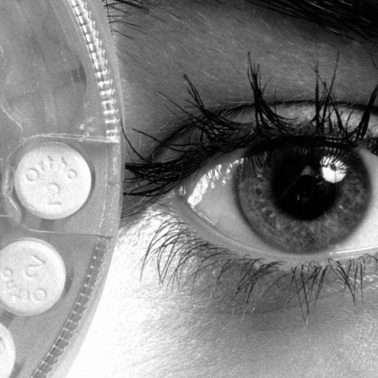 A woman holding birth control pills up to her face