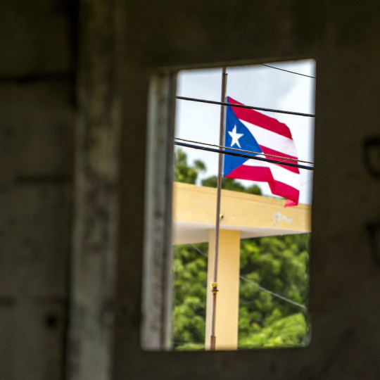 The Puerto Rican flag seen through the window of an abandoned building.