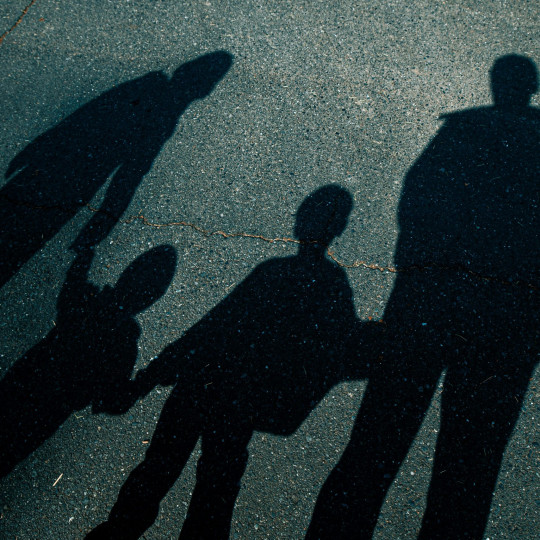 Shadows of a nuclear family on a street.