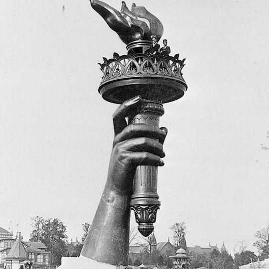 The arm of the Statue of Liberty holds aloft a flaming torch.