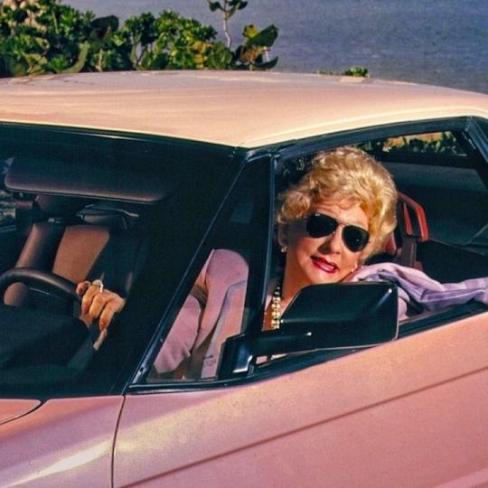 Mary Kay looks out the window of a pink car.