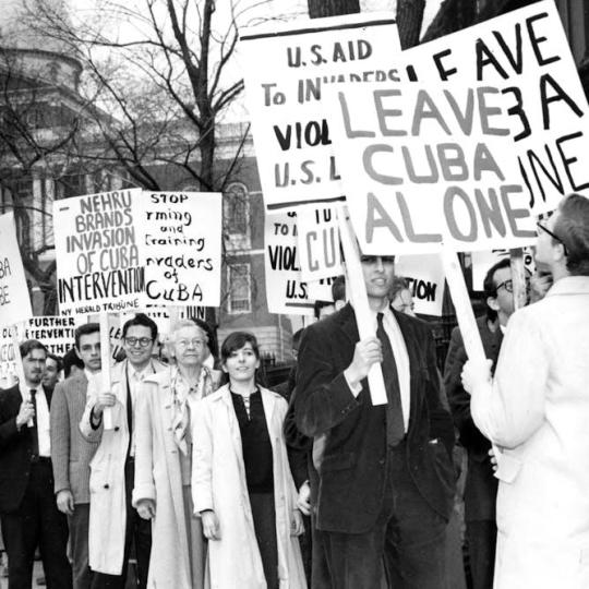American protestors hold signs discouraging the U.S. government from invading Cuba.