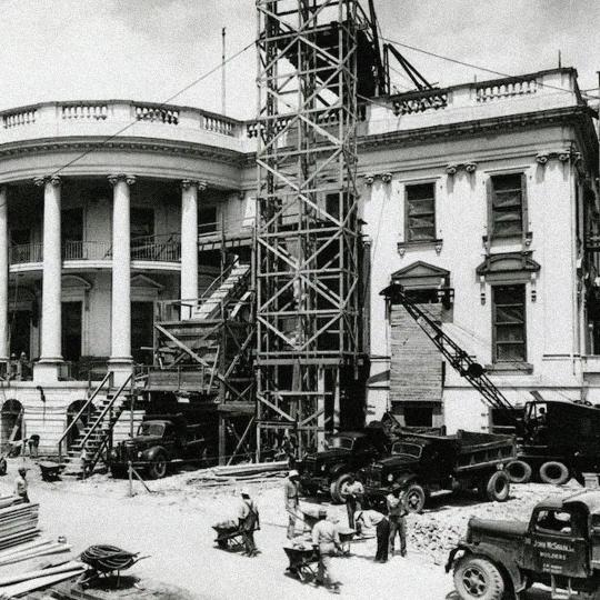 The White House undergoing renovation, with scaffolding and construction materials outside.