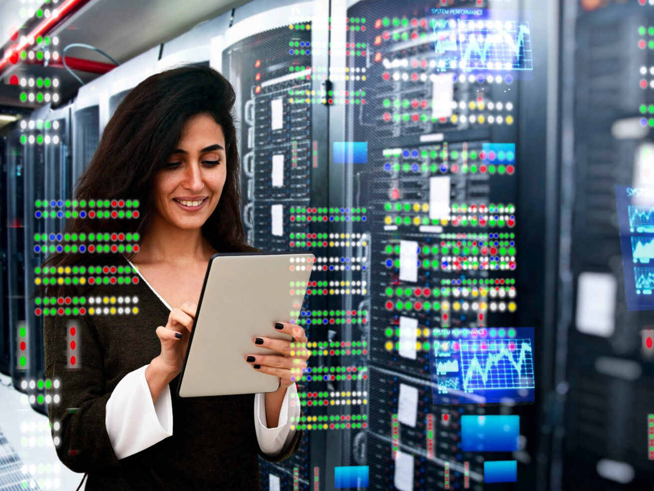 A woman stands in a server room, smiling and using a tablet, with digital data overlays and graphs displayed around her.