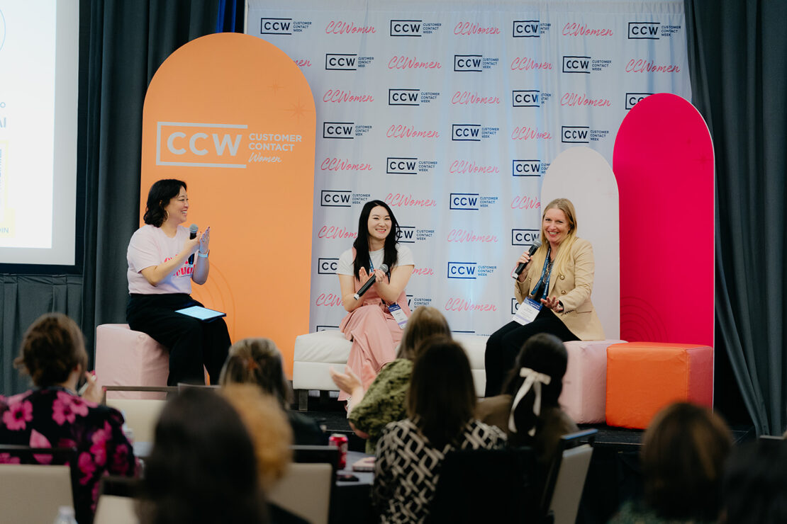 Three women sit on stage, speaking and smiling during a panel discussion at a CCW Customer Contact Women event, with an audience visible in the foreground.