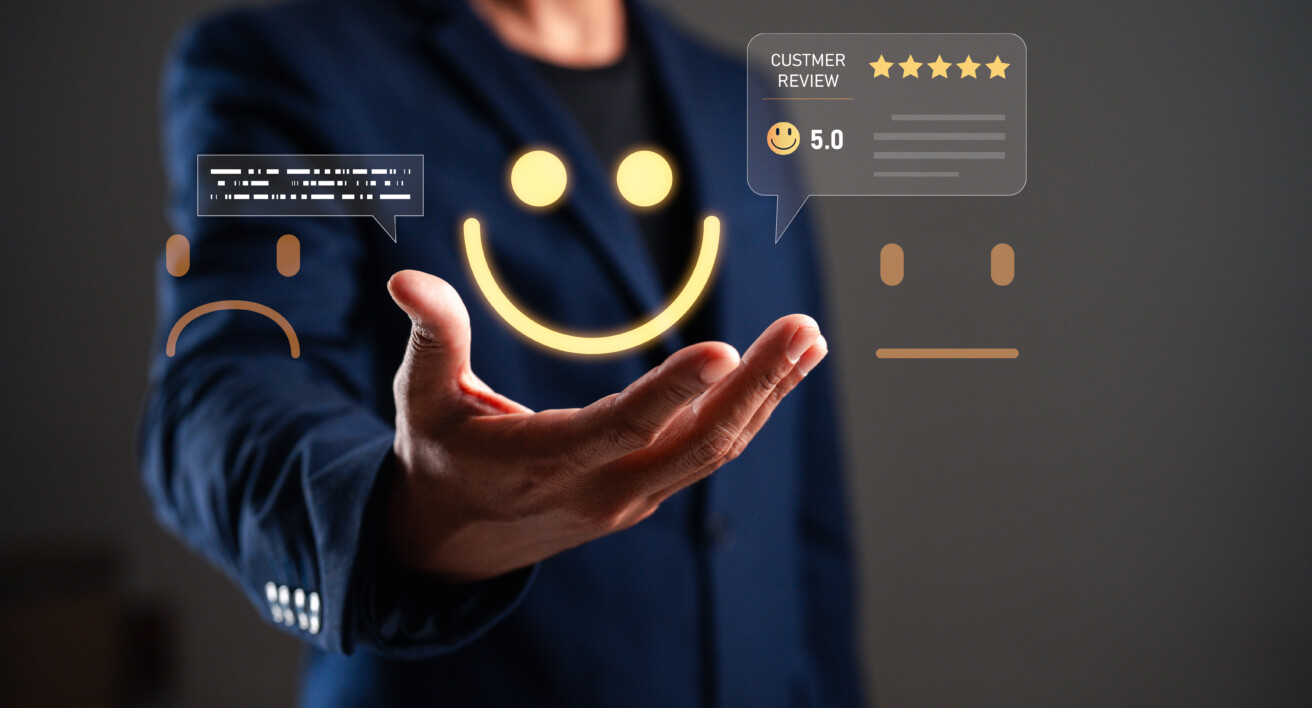 A person in a suit holds out their hand, with digital graphics of a sad face, neutral face, happy face, and a five-star customer review hovering above it.