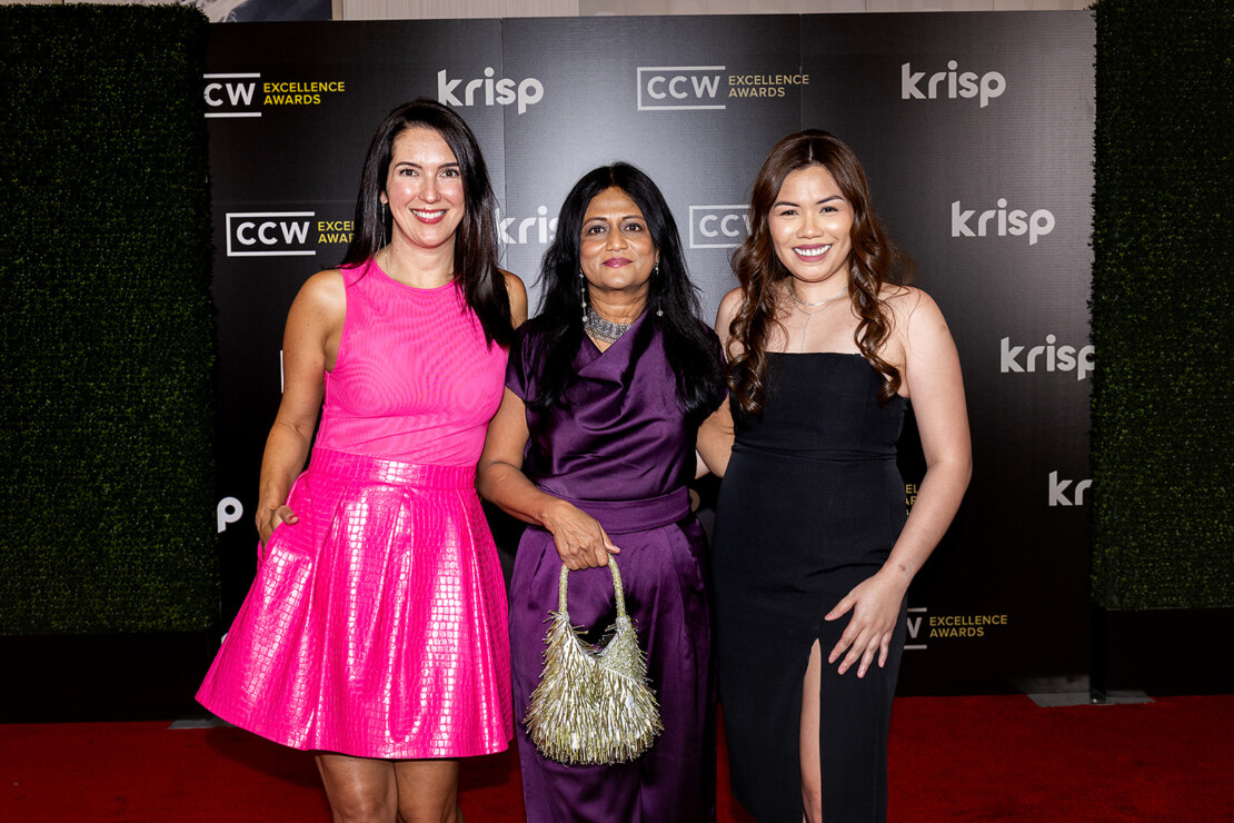 Three women pose together on a red carpet in front of a step-and-repeat backdrop for the CCW Excellence Awards.