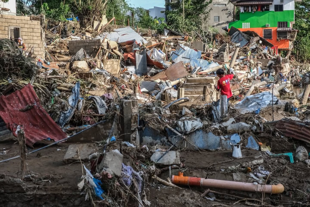 An individual working through rubble and following floodwaters.