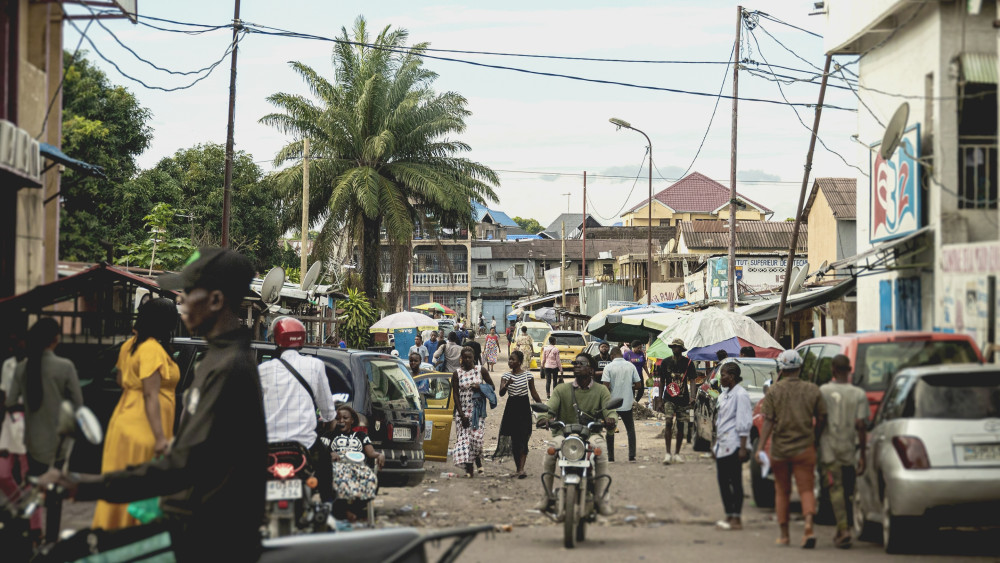 A busy street with people walking and riding motorcycles