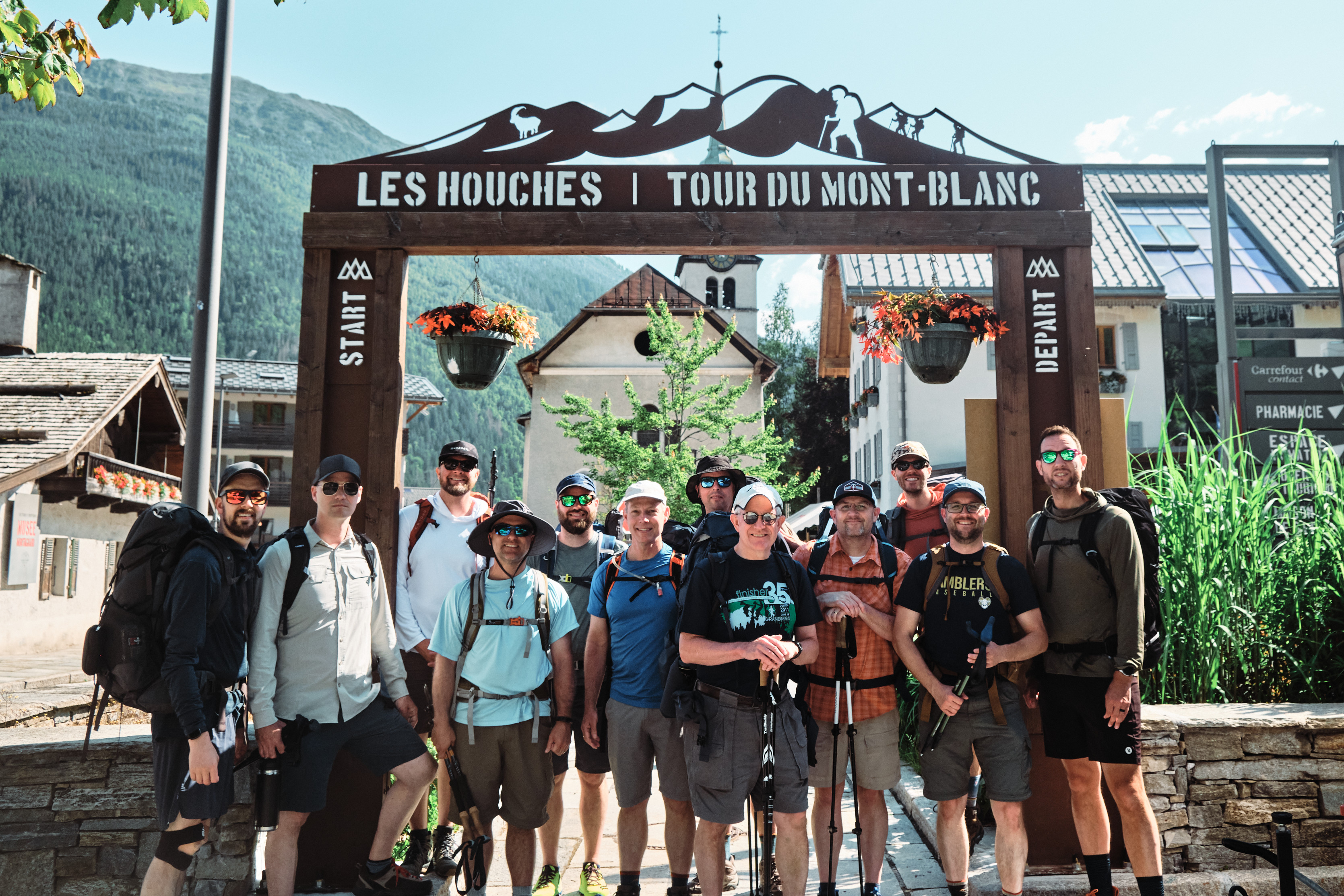 A group of men in hiking gear stand in front of a gate