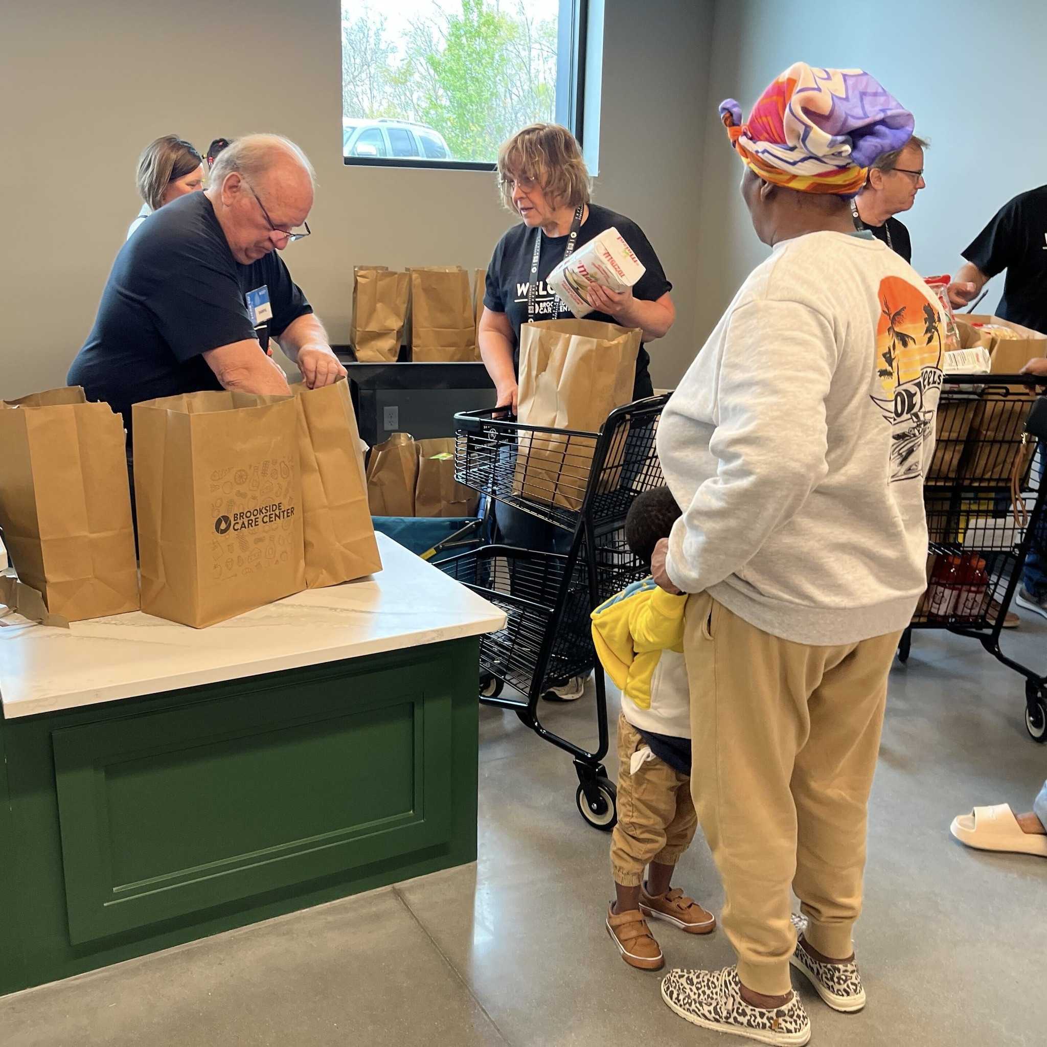 A volunteer helps shoppers with their grocery bags.