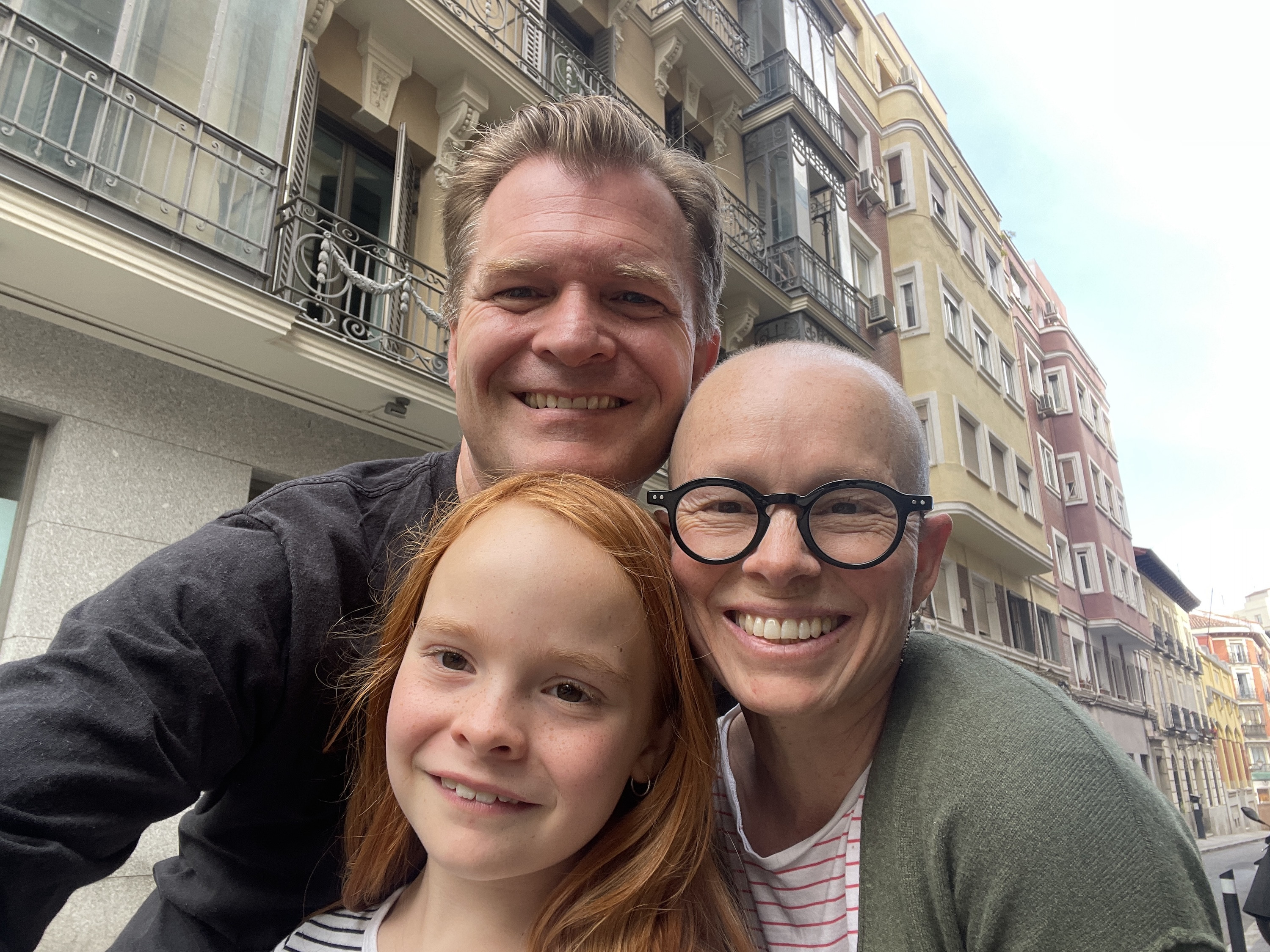 A family of three in front of a row of European-style buildings