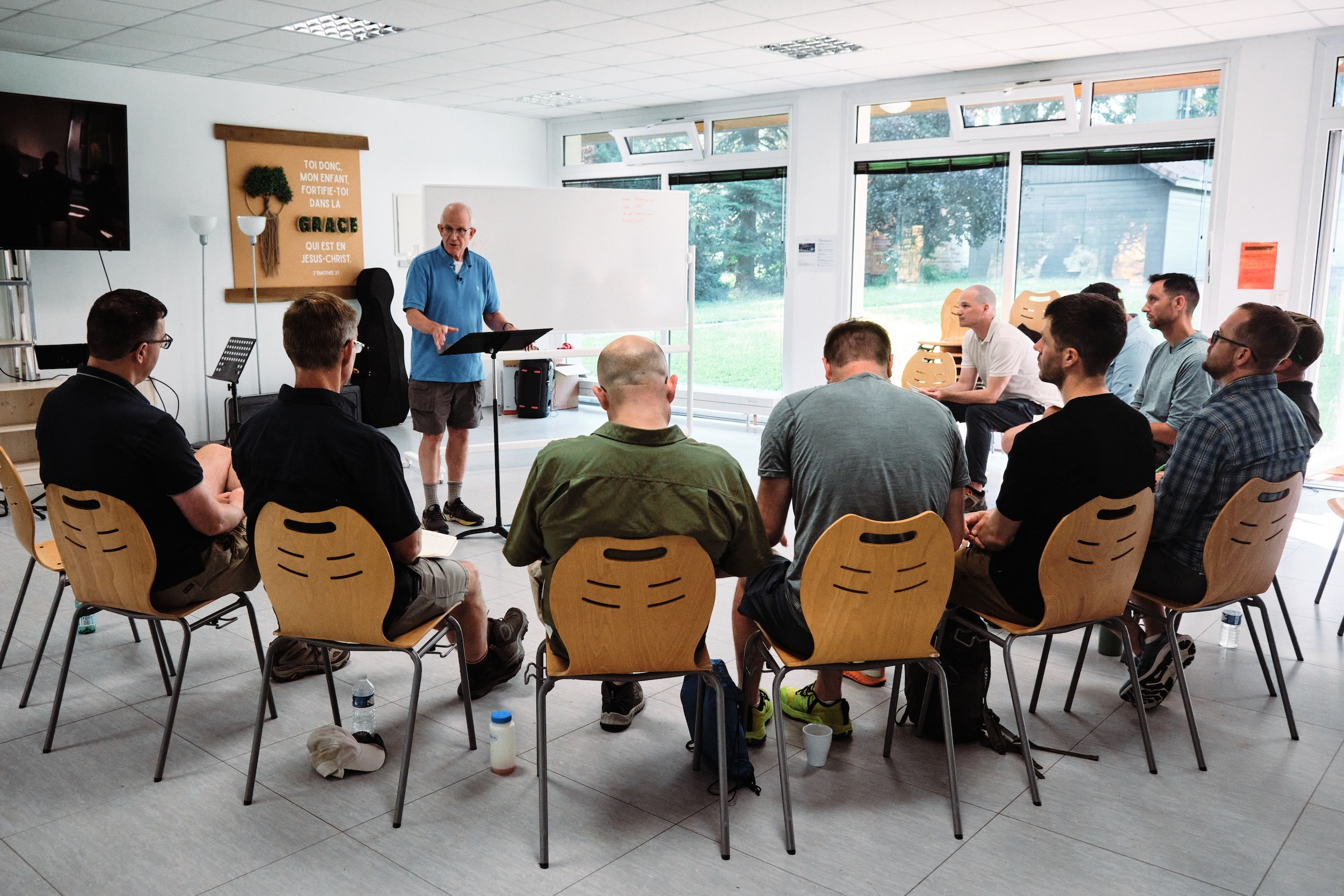 A group of men sitting in a semi-circle around a teacher
