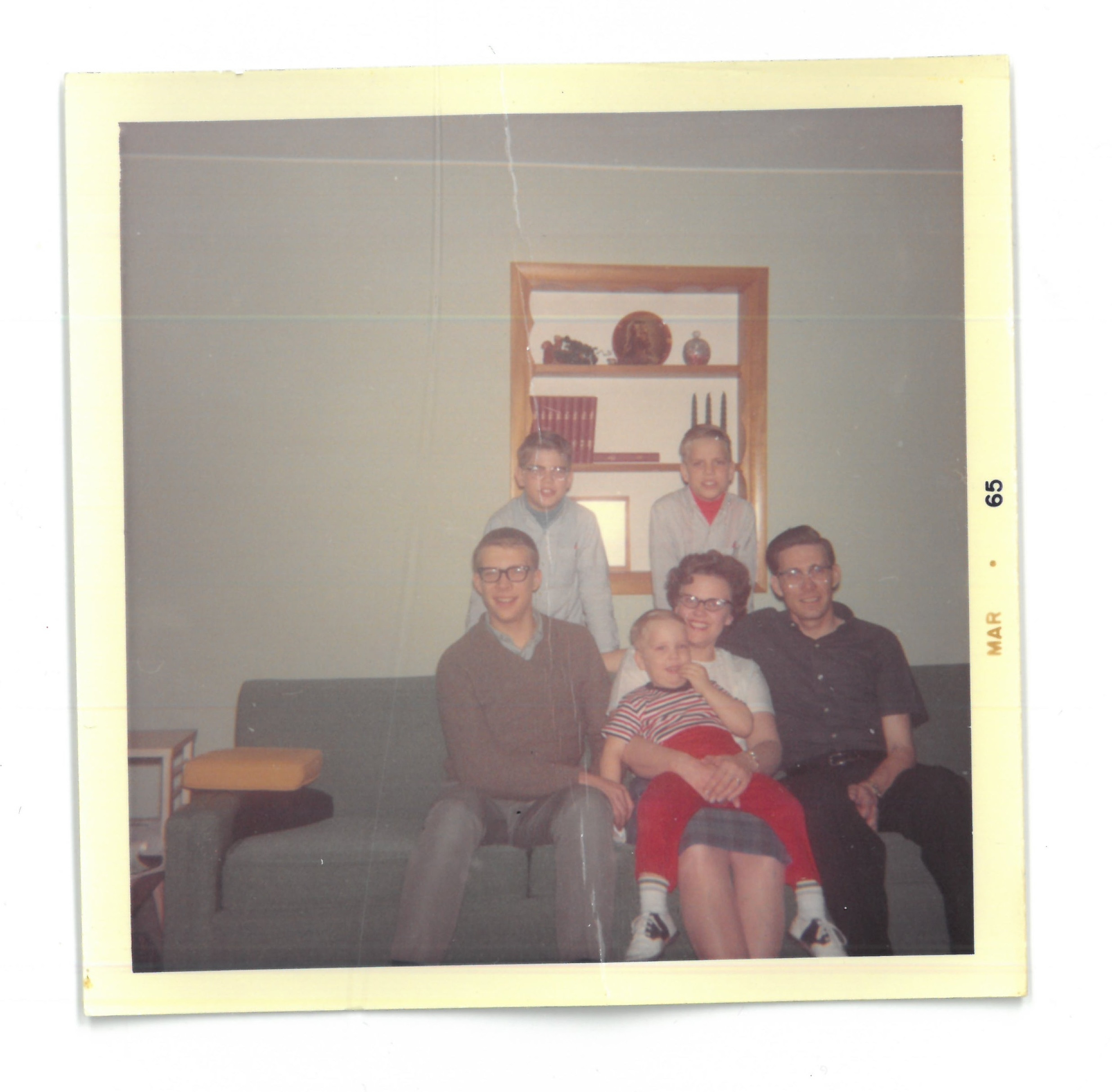 A family of six sits on a couch together