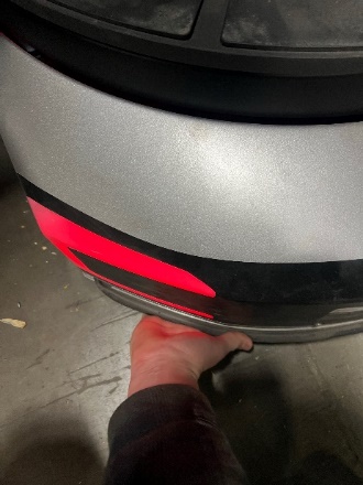 A person's foot on a silver car

Description automatically generated
