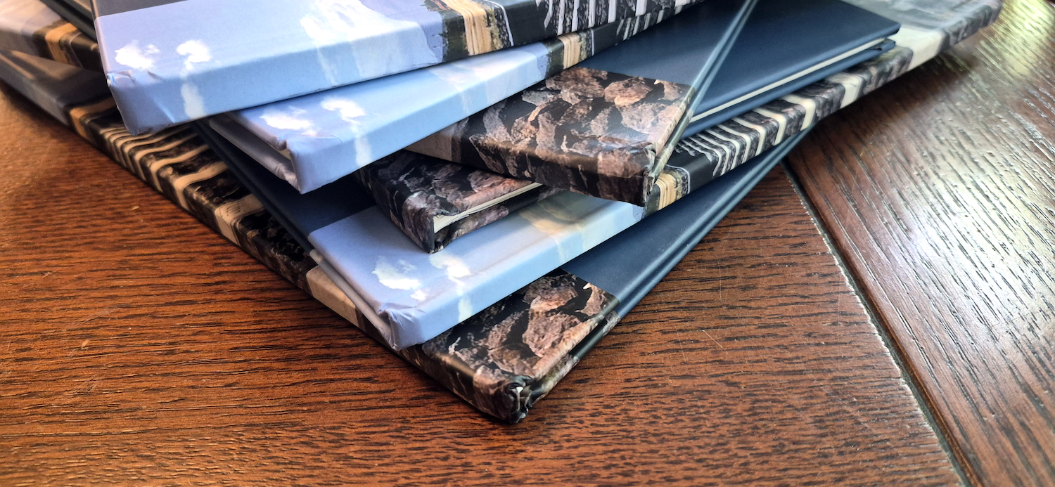 Mehrere aufeinandergestapelte Bücher, bei denen die eingedrückten Ecken und beschädigten Kanten deutlich sichtbar sind.
