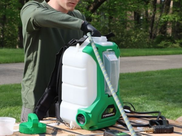 man filling sprayer with a garden hose